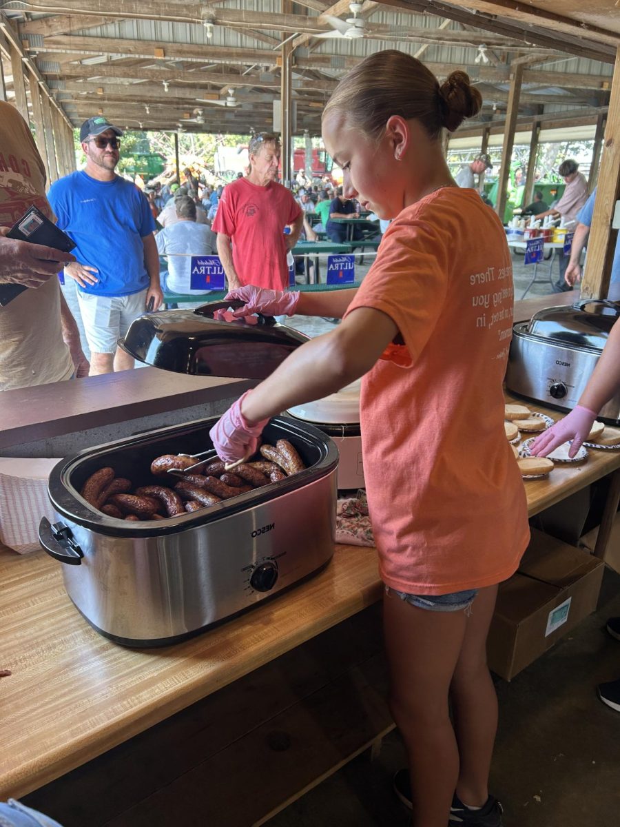 Freshman, Brooklyn Meier, serves a farmer at the auction.